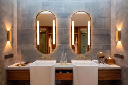 two sinks in a bathroom with two mirrors at Sumitra Luxury Villas A Pramana Experience in Sanur