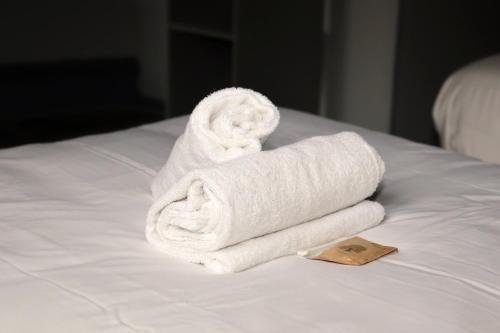 a stack of towels sitting on top of a bed at Hôtel & Restaurant Le Patio VICHY in Vichy