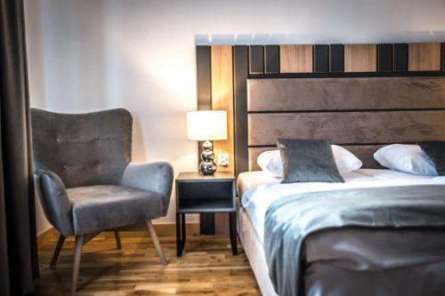 1 dormitorio con 1 cama, 1 silla y 1 lámpara en Hotel Sukcesor, en Zamość