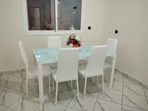 a white dining room table and chairs with flowers on it at AlMohit Larache in Larache