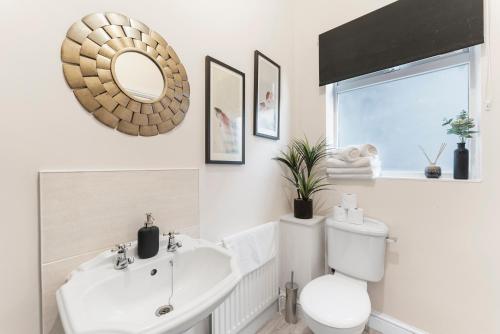 ein Badezimmer mit einem Waschbecken, einem WC und einem Spiegel in der Unterkunft Exquisite Flat - Parking - Sleeps 9 in Bristol