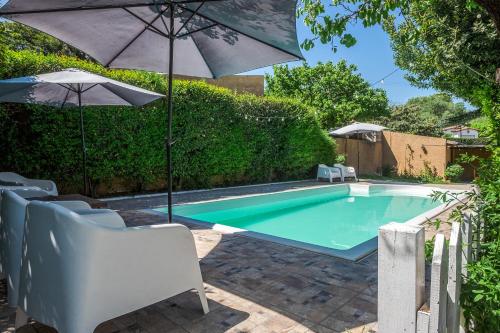 a swimming pool with an umbrella and chairs at Casa de Campo in La Falda
