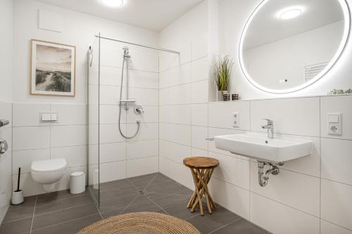 ein weißes Bad mit einem Waschbecken und einer Dusche in der Unterkunft Ostseebrise Olpenitz in Olpenitz