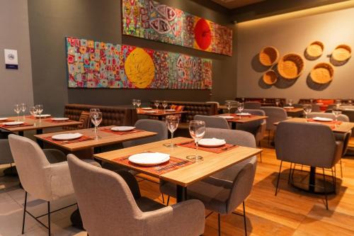 a dining room with tables and chairs and paintings on the wall at Novotel Curitiba Batel in Curitiba