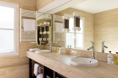 a bathroom with two sinks and a large mirror at Le Plessis Grand Hotel in Le Plessis-Robinson