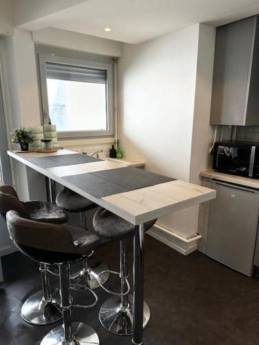 une cuisine avec un comptoir avec tabourets de bar et une fenêtre dans l'établissement L’Esquile Rose - Charmant studio en hypercentre, à Toulouse