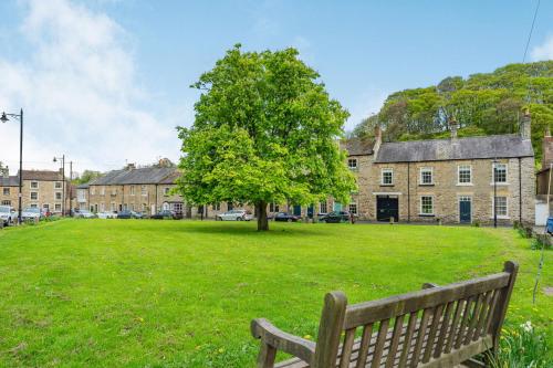 a park with a bench and a tree and buildings at Bay Tree Cottage in Richmond