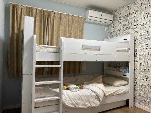 - białe łóżko piętrowe w niewielkim pokoju w obiekcie 幸町HOUSE w Tokio