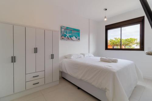 ein weißes Schlafzimmer mit einem Bett und einem Fenster in der Unterkunft Apartamentos a 240m do mar Floripa-SC ADC in Florianópolis