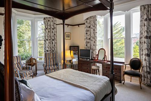 Un dormitorio con una cama, un escritorio y ventanas. en The Elmfield, 8 Bed Villa with heated indoor Swimming Pool and Cocktail Bar, en Ilfracombe