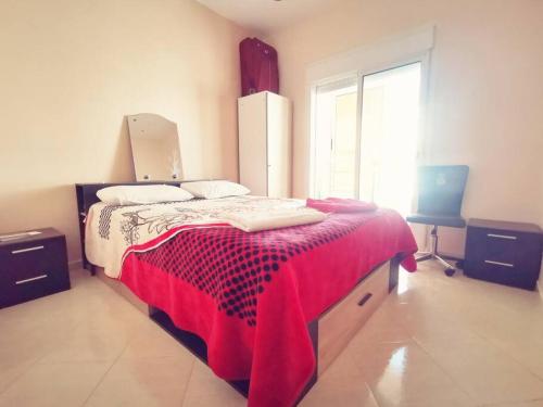 a bedroom with a large bed with a red blanket at Nadushka Voyage appartement in Agadir in Agadir
