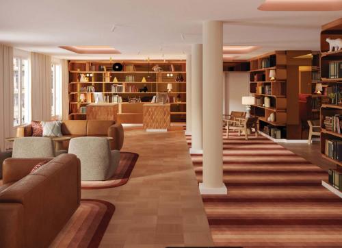 a living room with couches and bookshelves at Le Plessis Grand Hotel in Le Plessis-Robinson