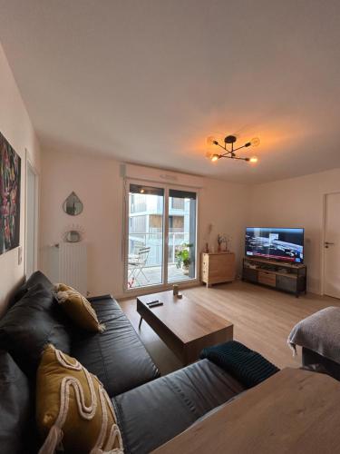 ein Wohnzimmer mit einem Sofa und einem Tisch in der Unterkunft Chic & moderne appartement - proximité métro in Asnières-sur-Seine