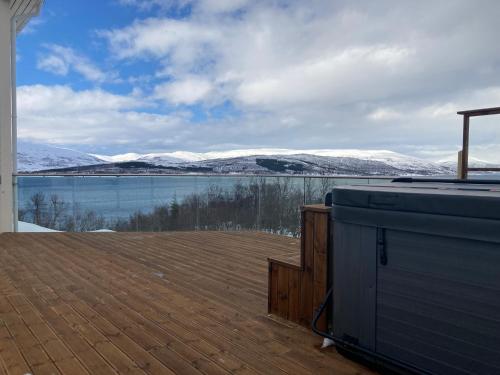 a deck with a view of a lake and snow covered mountains at New Aurora Hotspot - Studio Nordspissen in Tromsø