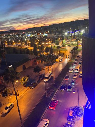 una città con auto parcheggiate in strada di notte di Appart Hotel Monaco a Tangeri