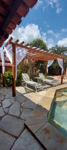 a patio with chairs and a pergola and a pool at Pousada Rancho do João in Pirenópolis