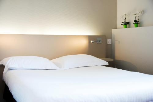 a bed with white sheets and two pillows at Le Germinal in Cesson-Sévigné