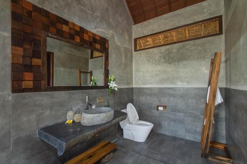 a bathroom with a sink and a toilet and a mirror at Ubud Luwih Nature Retreat in Ubud