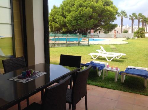 a table and chairs with a view of a pool at 2 bedrooms appartement at Ciutadella de Menorca 200 m away from the beach with shared pool and enclosed garden in Cala en Bosc
