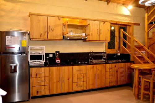 eine Küche mit Holzschränken und einem Kühlschrank aus Edelstahl in der Unterkunft Casa Kambana en Vilcabamba in Loja