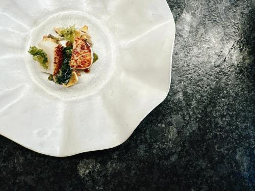a white plate with food on a table at Am Pfarrhof - Gourmethotel by Harald Irka in Sankt Andrä-Höch