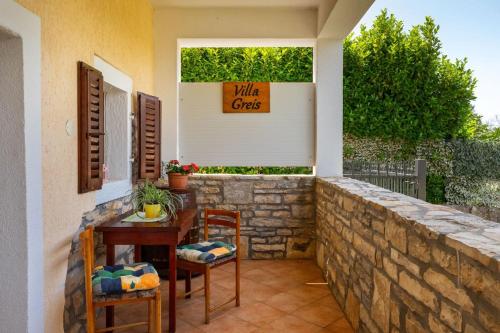 a patio with a table and chairs and a wall at Villa Greis with 4 bedrooms and pool in Buje in Momjan