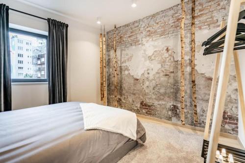 een slaapkamer met een bakstenen muur en een bed bij L'appart Léon, avec sauna in Luik