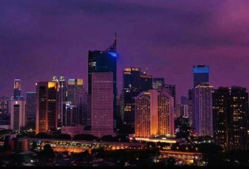 a lit up city skyline at night with at Cosmo Residence “ 1 BR ” at Thamrin City in Jakarta