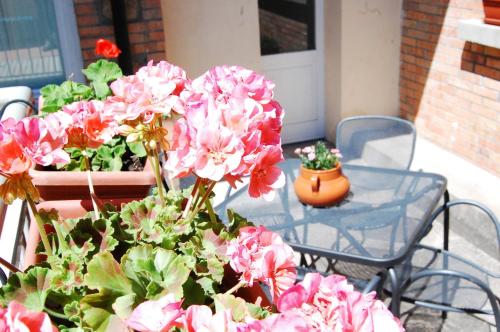 a patio with pink flowers and a table and a chair at Hotel La Locanda in Volterra