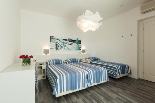 two beds in a white room with a chandelier at Albergo alla Spiaggia in Grado