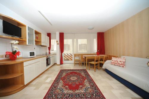 a living room with a bed and a kitchen with a table at Appartamento Dolomiti in Predazzo