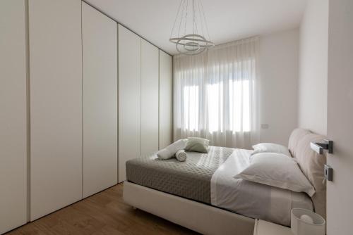 een witte slaapkamer met een bed en een raam bij La casa di GABRIELLA in Milaan