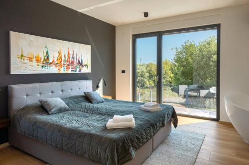 um quarto com uma cama grande e uma janela grande em Modern villa Cormoran with pool in Porec em Porec
