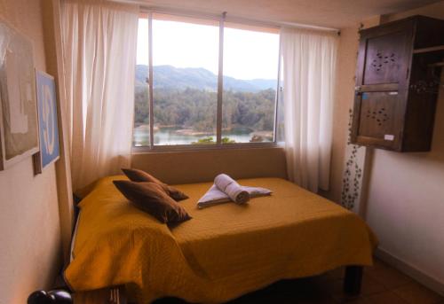 a bedroom with a bed and a window with a view at Casa Encuentro Ecolodge, Outdoor Gym and Yoga in Guatapé