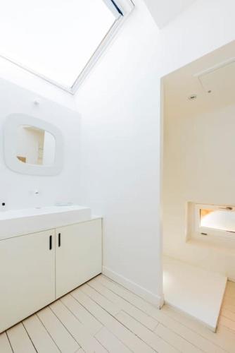 - une cuisine blanche avec une lucarne et des armoires blanches dans l'établissement Maison de caractère - Brique rouge, à Pechbusque