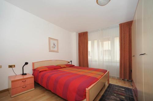 a bedroom with a bed and a dresser and a window at Appartamento Dolomiti in Predazzo