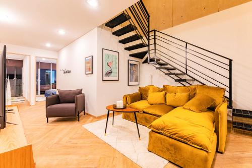 a living room with a yellow couch and a staircase at Trendy La Roma Condo with Parking & Patio in Mexico City
