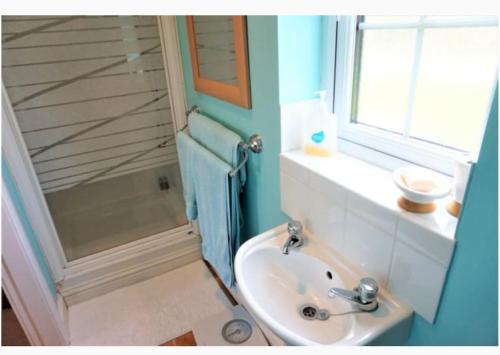 a bathroom with a sink and a window and a shower at Large modern house in small rural Hamlet. in Duddon