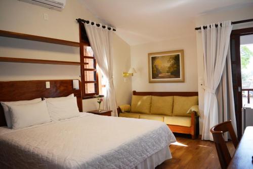 a bedroom with a bed and a couch at Pousada O Garimpo. in Embu