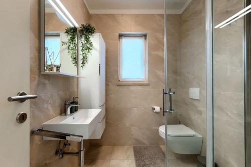 a bathroom with a sink and a toilet and a shower at Modern villa Oliveti with pool and grill in Porec in Frata