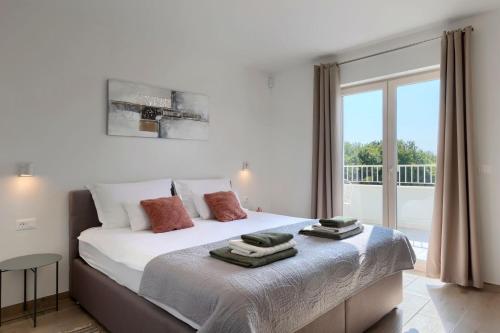 a bedroom with a large white bed with a balcony at Modern villa Oliveti with pool and grill in Porec in Frata