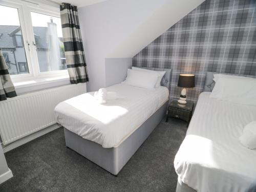 a bedroom with two beds and a window at Hunters Cottage in Benllech