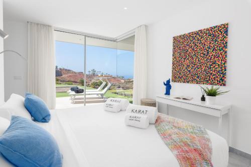 una camera bianca con un letto bianco e una grande finestra di Karat Villa Zambrano a Guía de Isora