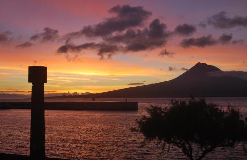 a sunset over a body of water with a mountain at Residência Machado in Horta