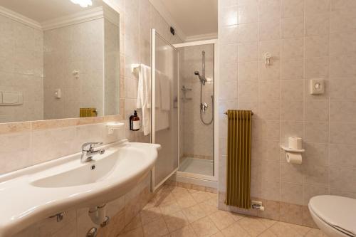 a bathroom with a sink and a shower and a toilet at Flos Hotel in Moena