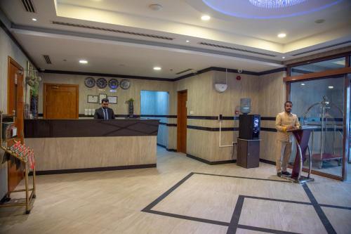 two men standing in an office lobby with a counter at Juffair Trends Luxury Apartment in Juffair