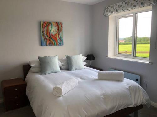 a white bed in a bedroom with a window at 2 Bedroom cottage with Beautiful views over the Mendips in Radstock