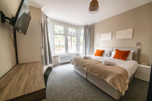 a bedroom with a bed with orange pillows and a television at NEWLY REFURBISHED House - FREE Wi-Fi! in Wyken