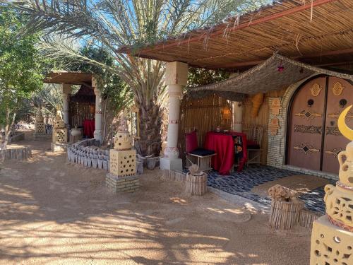 un patio con una casa con una mesa y una parrilla en Tente et Restaurant ElBey, en Douz