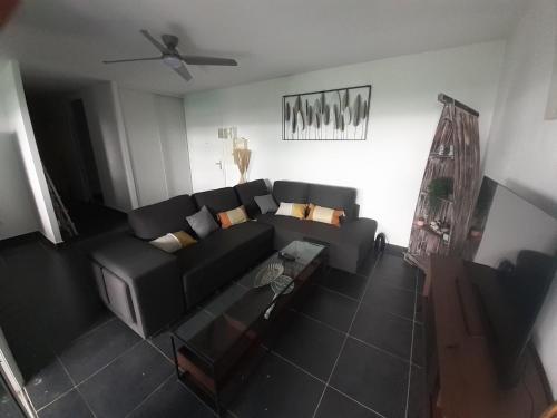 einen Blick über ein Wohnzimmer mit einem schwarzen Sofa in der Unterkunft Appartement spacieux moderne lumineux avec grand jardin dans résidence avec piscine in Le Gosier